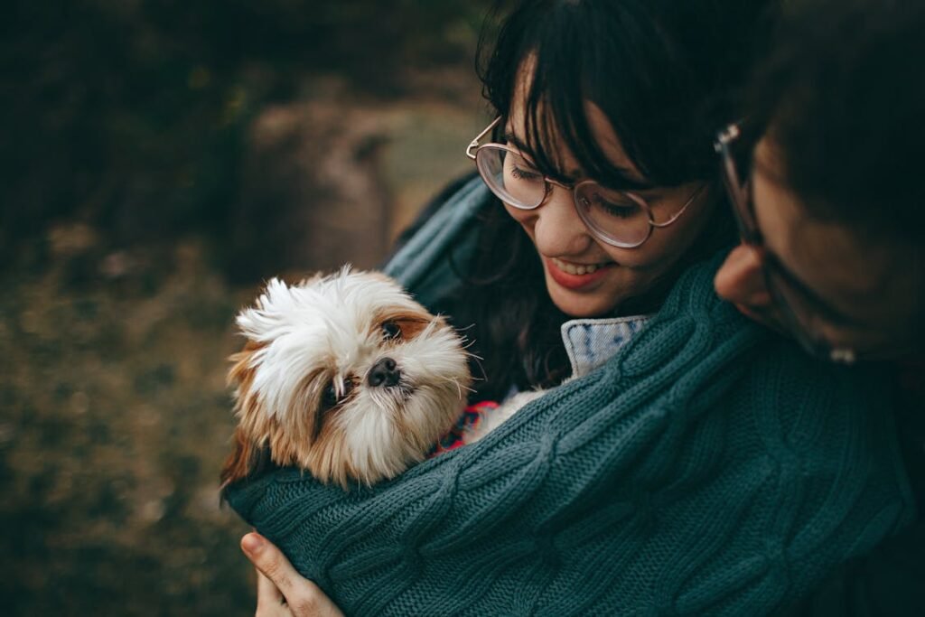 Free A woman lovingly cuddles her Shih Tzu puppy, wrapped in a warm blanket outdoors. Stock Photo