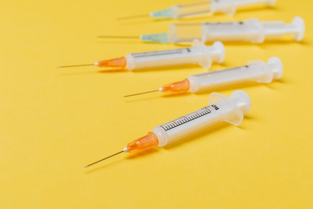 Free Close-up of sterile disposable syringes on a vibrant yellow surface. Stock Photo