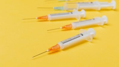 Free Close-up of sterile disposable syringes on a vibrant yellow surface. Stock Photo